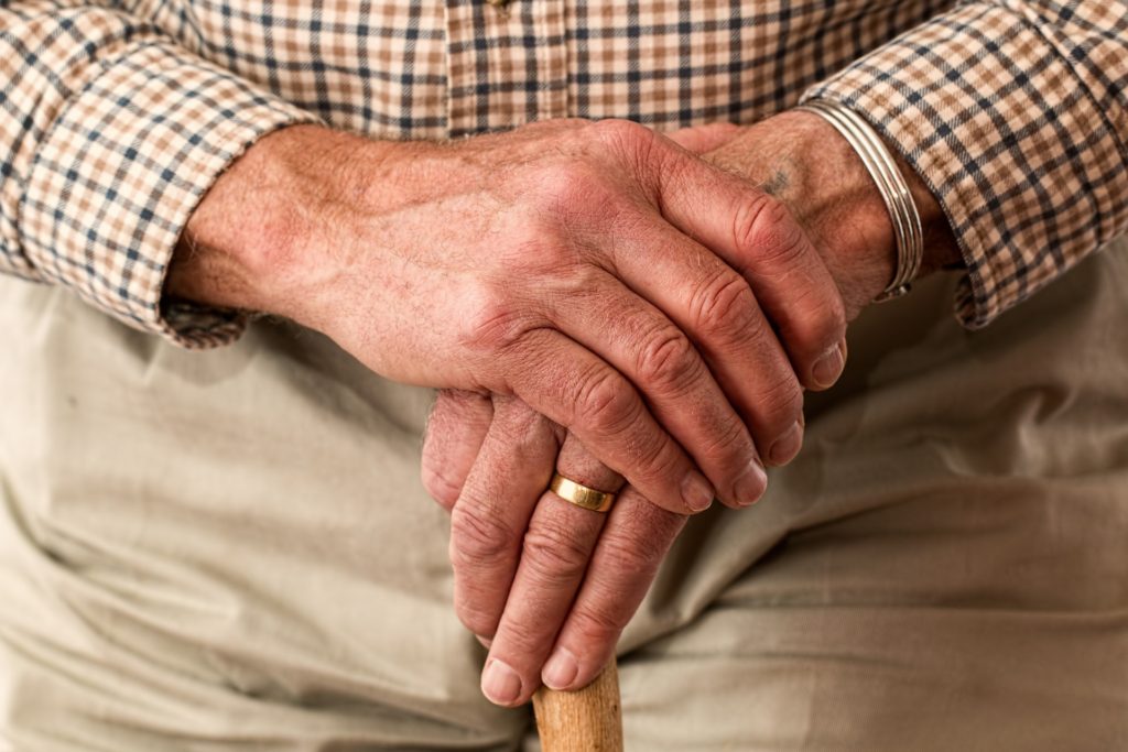 Image of elderly man with hands clasped over his cane